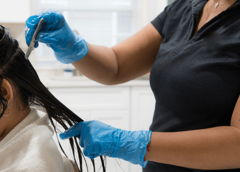 A technician combs through a child's hair during mobile lice treatment